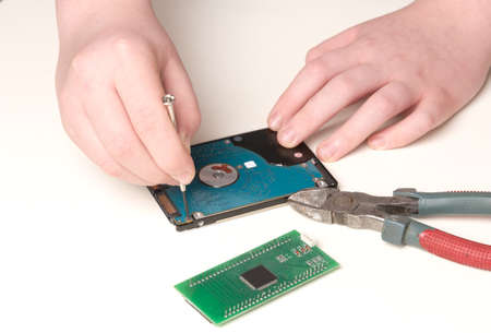 Hard drive repair with screwdriver by human handsの写真素材