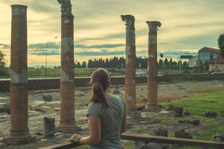 A woman near the great marble column of old building tempel. Tourist at the Museum excavations of the ancient cityの写真素材