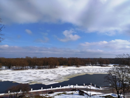Beautiful winter landscape with frozen river and blue sky with white cloudsの写真素材