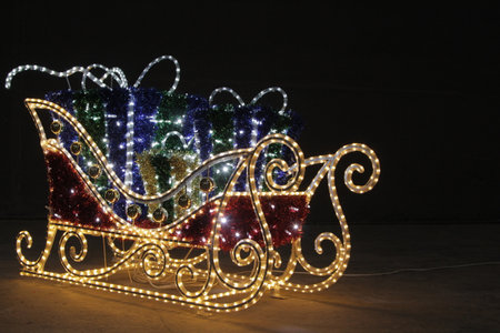 Christmas presents in sleigh with lights on black backgroundの写真素材