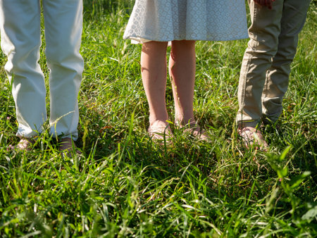 Legs of young people walking on green grass in parkの写真素材