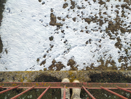 View looking down at snow-covered ground from a metal railing