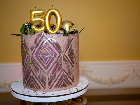 Number 50 on a pink cake with gold decorations and a garlandの写真素材