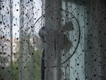 The wind blows on the window of the house with a fan.の写真素材