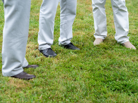 Legs of men standing on the green grass during a wedding ceremonyの写真素材