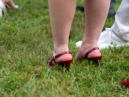 A closeup shot of a woman wearing red shoes on the grassの写真素材