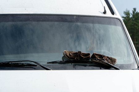 Close-up of dirty shoes on the hood of a white carの写真素材