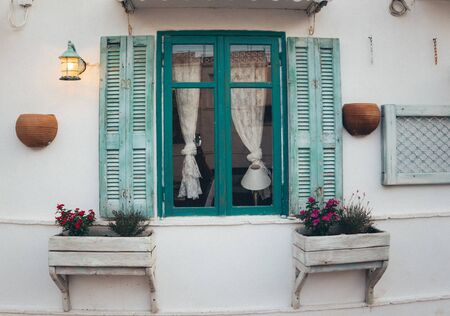 Traditional house wall with open blue window shutters.