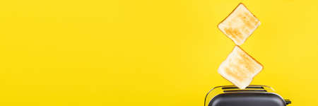 Slices of toast jumping out of the toaster against yellow background.の写真素材