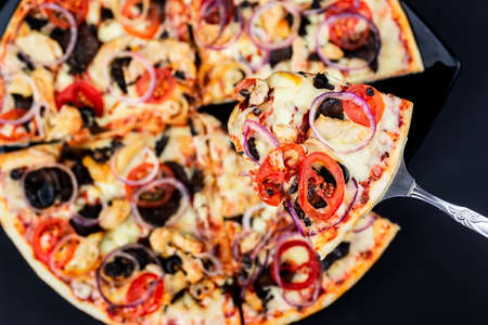 Delicious pepperoni pizza and basil tomato ingredients on a black concrete background. Top view of hot pepperoni pizza. With space for copying text. The apartment was lying there. Banner adの写真素材