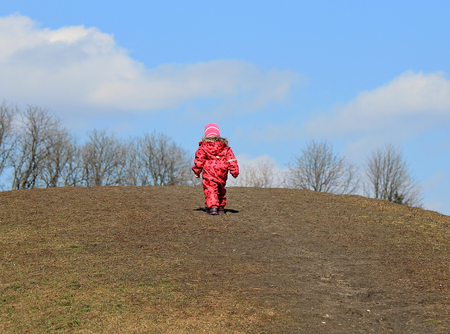 a little girl climbs the hill with difficultyの写真素材