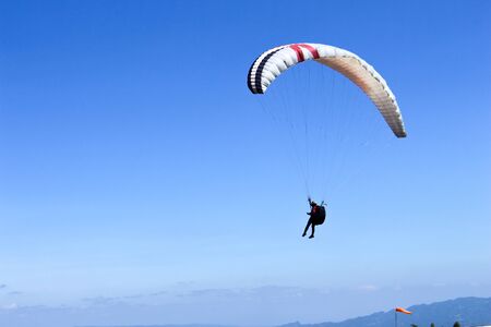 paraglider flying in blue sky on valleys landscape in Indonesiaの写真素材