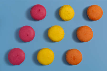 Crimson, yellow and orange macarons on a blue backgroundの写真素材