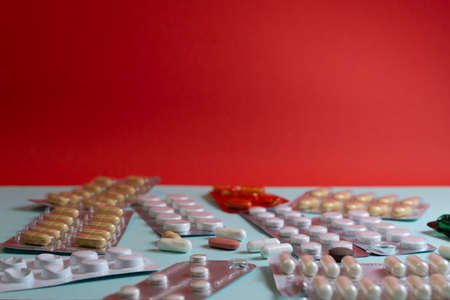 White, red and yellow pills on blue background with a hard shadowの写真素材