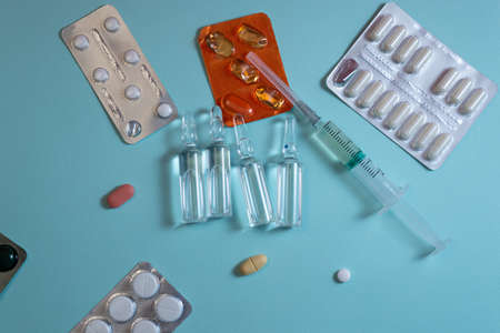 Glass ampoules, pills in blister pack and syringe lying on blue backgroundの写真素材