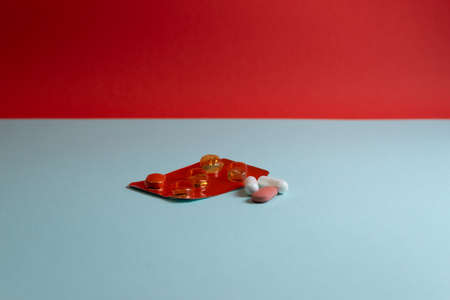 White, red and yellow pills on blue background with a hard shadowの写真素材