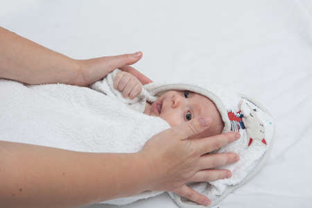 Mother hand cleaning baby ear and nose with a cotton swab. Baby taking care and hygiene concept.