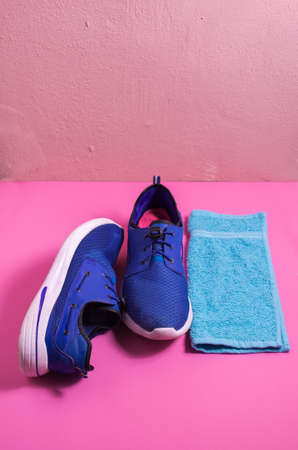 blue sports shoes on an isolated pink background, blue towel for sports accessory, fitness concept. . shot from above, trendy contrasting colorsの写真素材