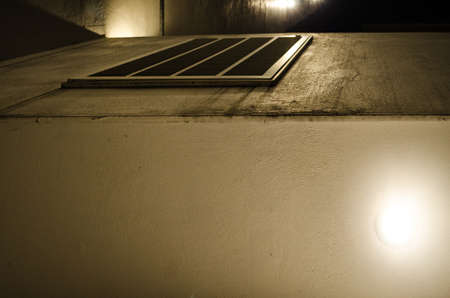 spots of yellow lights outside a gray building, on the urban street of the city with pattern of...