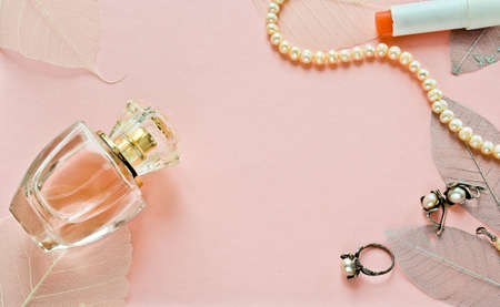 A transparent bottle of female perfume on a gentle background with pearls ornaments