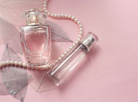 Glass bottle of female perfume on a delicate pink background with decorative leavesの写真素材