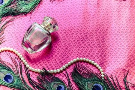 female perfume on a bright pink background and peacock feathersの写真素材