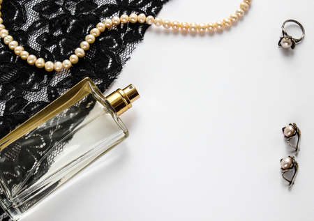 Glass female bottle on a white background and lace with pearl jewelry
