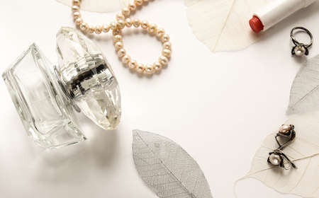 Female perfume and accessories on a white gentle background with decorative leavesの写真素材