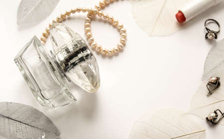 Female perfume and accessories on a white gentle background with decorative leavesの写真素材