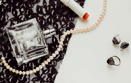 Glass female bottle on a white background and lace with pearl jewelryの写真素材