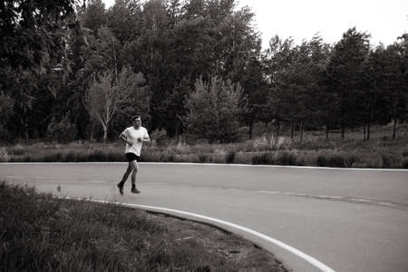 A guy runs in the summer on an asphalt road, doing sportsの写真素材