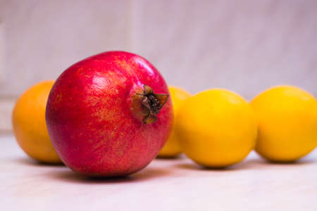 red ripe pomegranate on a table on a background of yellow fruitsの写真素材
