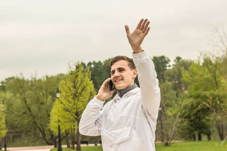 a young guy waving his hand and talking on the phone, meeting friends