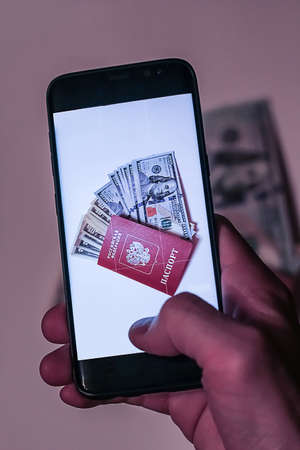 hand with phone photographing passport with dollarsの写真素材