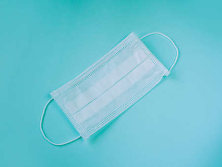 protective white medical mask on a blue background, a means of protection against the virusの写真素材