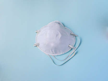 protective white medical mask on a blue background, a means of protection against the virusの写真素材