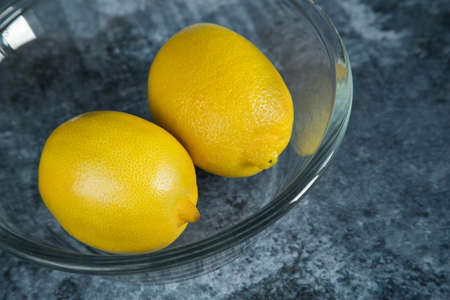 Fresh ripe lemons in glass bowlle table, closeupの写真素材
