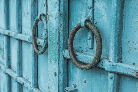 Old rusty metal door handle close up. Turquoise background.