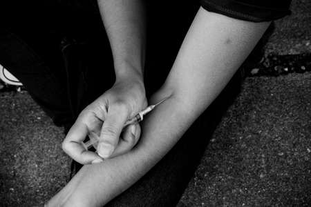 Image of a woman using a syringe. Concepts of drug addiction. Add vignette filterの写真素材