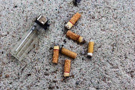Lighter and cigarette butts on the ground.の写真素材