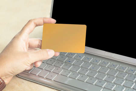 Beautiful girl holding a credit card and typing. Online shopping on the internet using a laptop.の写真素材