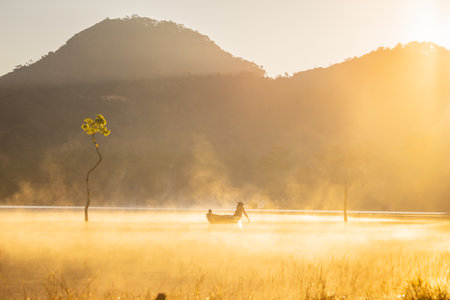 Fisherman in boat on the lake at sunrise, Thailand.の写真素材