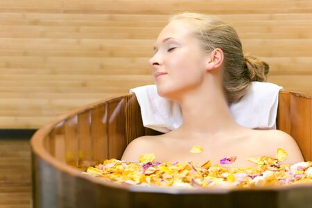 The young woman has a session spa in a wooden bathの写真素材