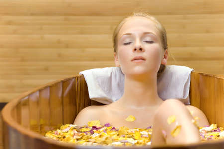 The young woman has a session spa in a wooden bathの写真素材