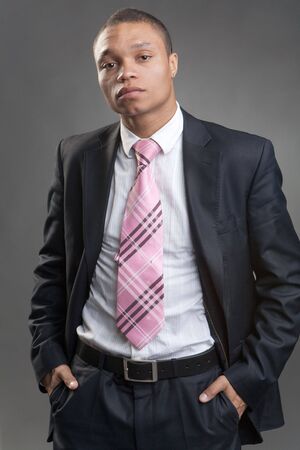 The businessman holds hands in pockets on a dark backgroundの写真素材