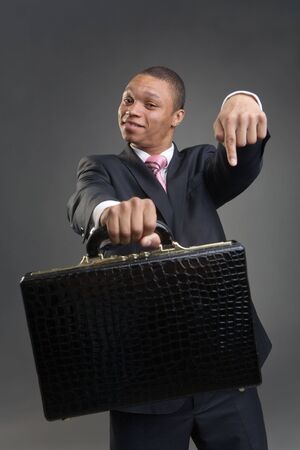 The happy businessman offers briefcase on a dark backgroundの写真素材