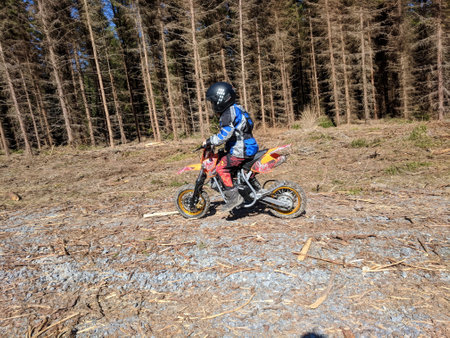 A little boy is enjoying his motocross ride in various poses on nature trails.