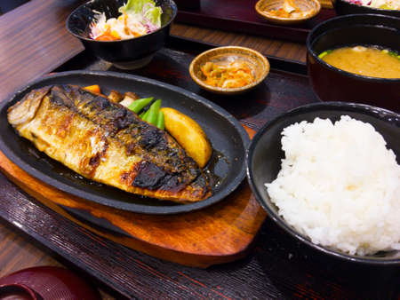 Set of Japaneses dishes consists of grilled seabass fish with soy sauce and vegetables with carrots, mushroom, asparagus and potatoes. In addition, the dishes also include salad dressing, kimchi, miso soup and plain rice.の写真素材