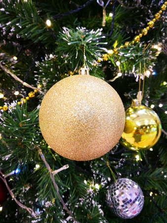 Close-up beautiful golden shiny ball is decorated on artificial tree, for happiness event such as...