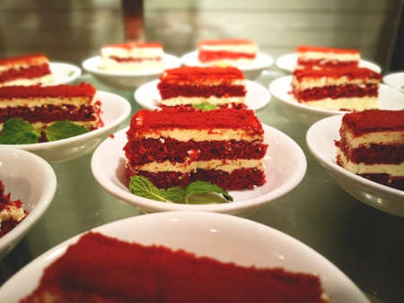 Red velvet cake on a white plate, and decorated with mint leaves.